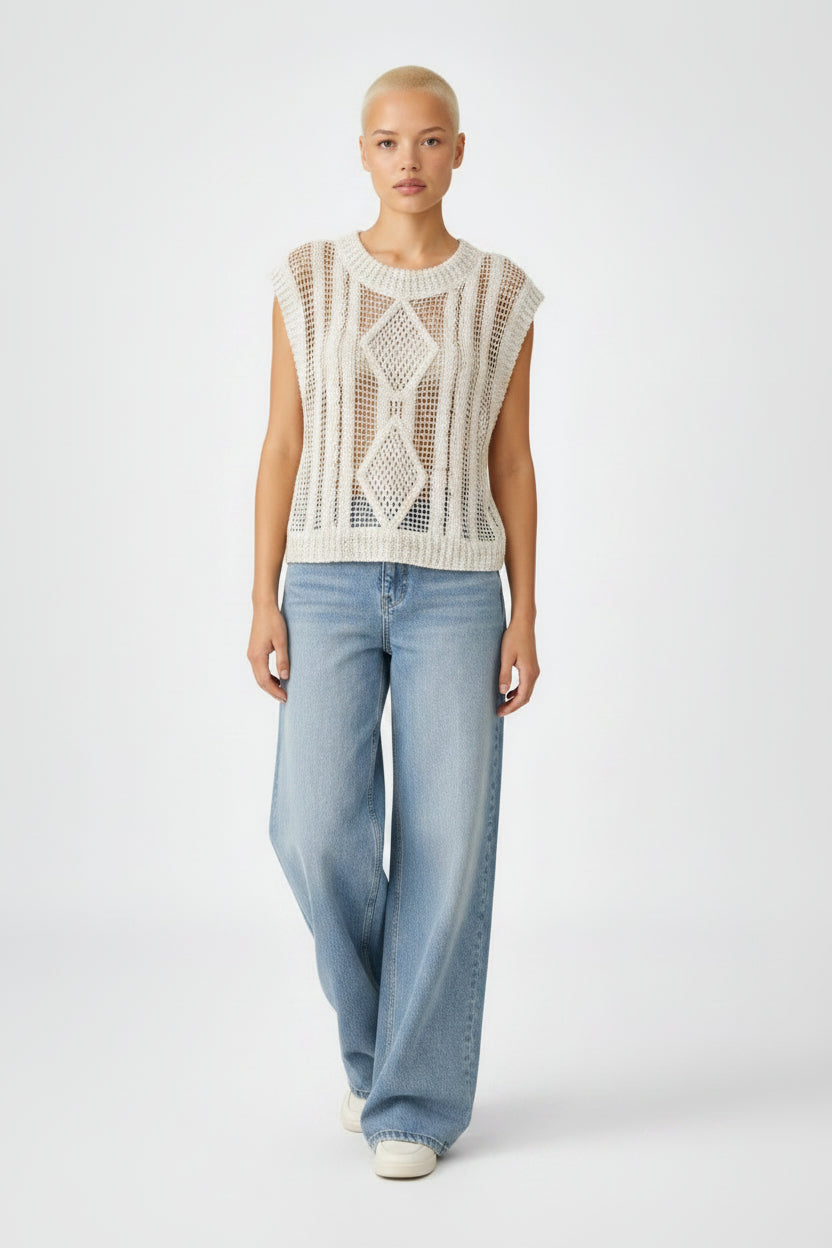 Woman wearing a sleeveless crochet top and blue jeans on a white background