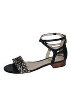 Black sandal with a patterned strap on a white background